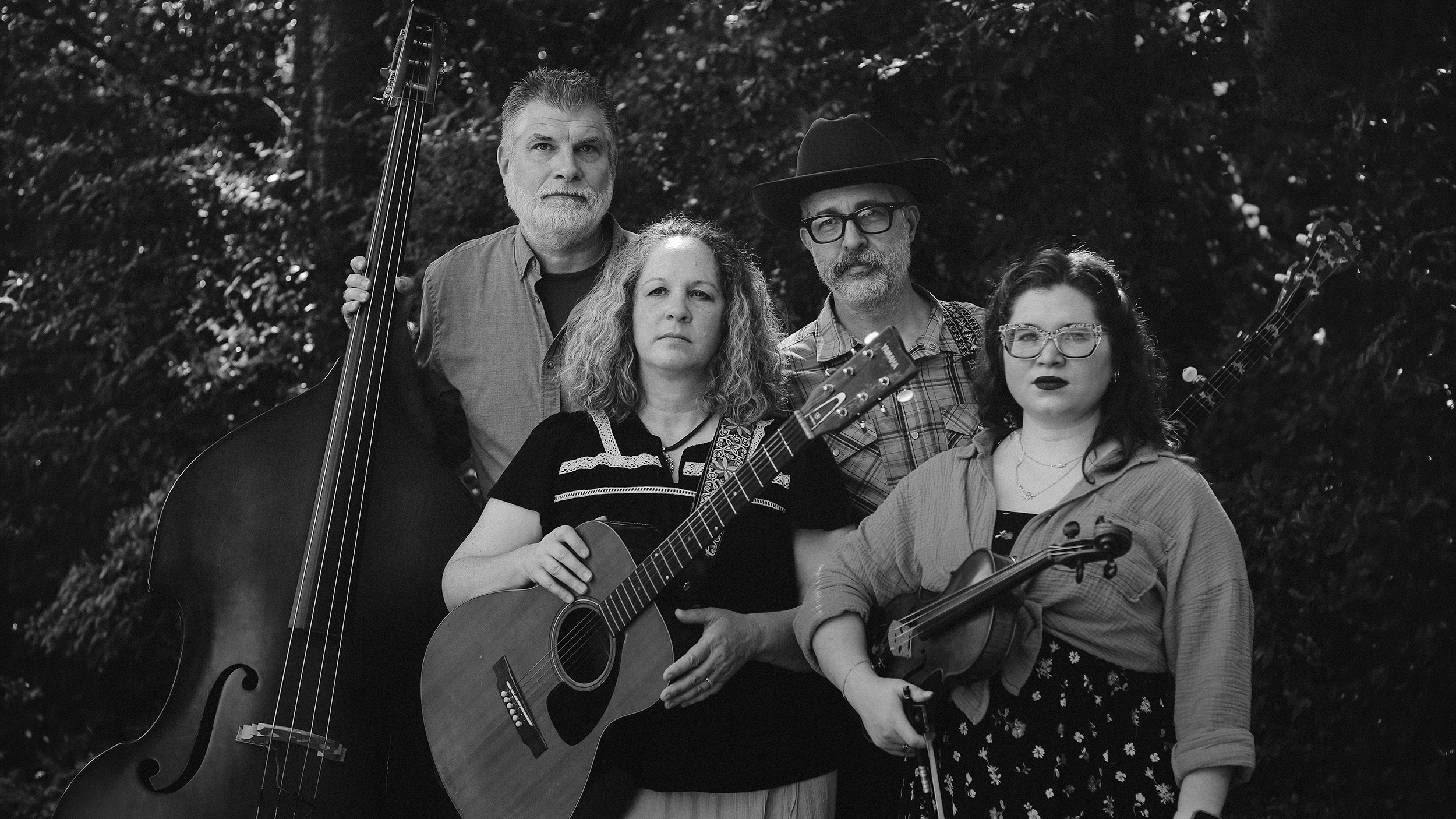 Black-and-white portrait of all four members of The Scrips with upright bass, guitar, banjo, and fiddle